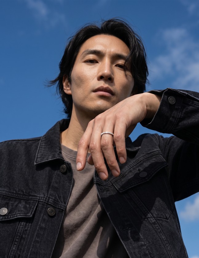 Model wearing a silver ring beneath a blue sky