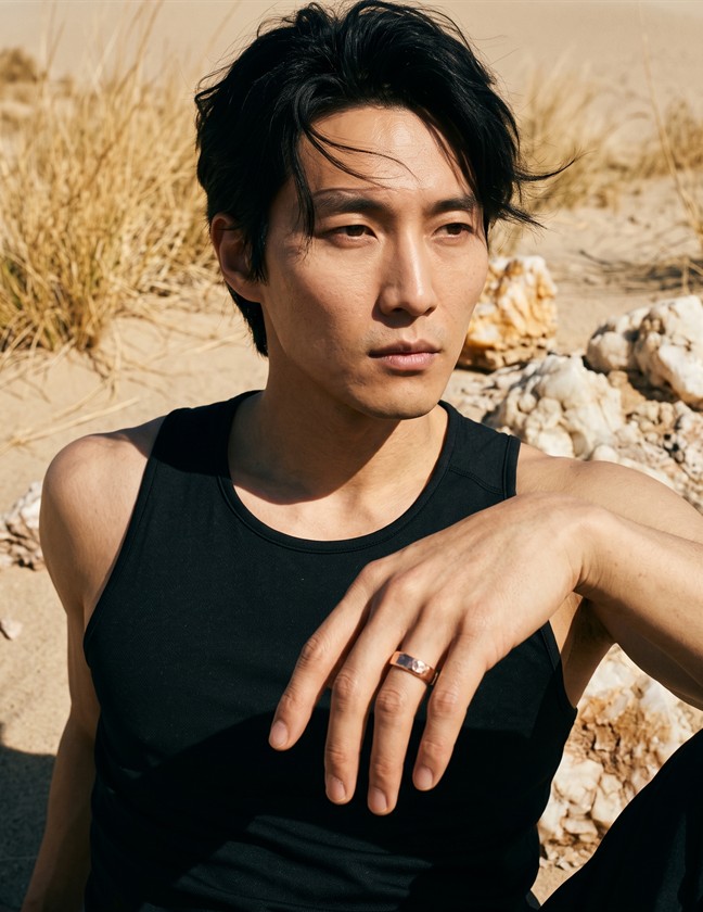 Model wearing a rose-gold ring in a desert setting